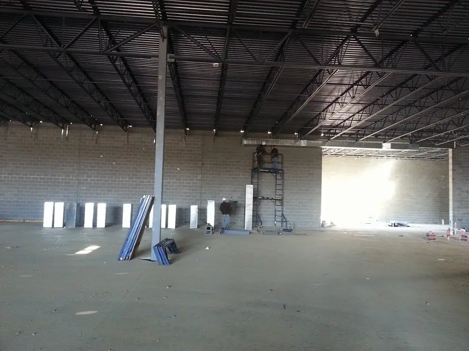 A large empty building shell with ductwork installation in progress