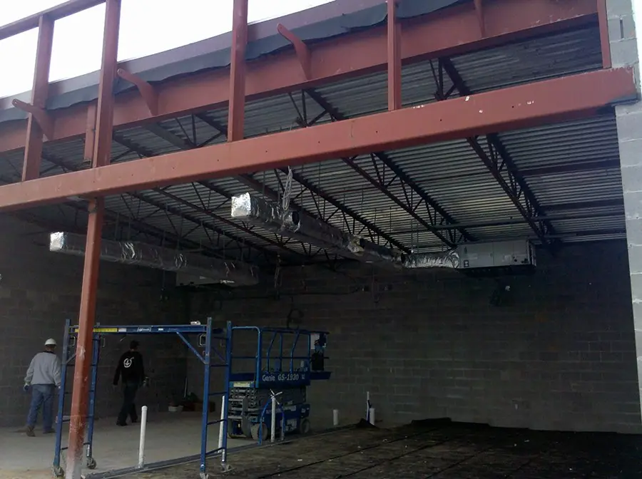 A steel building frame with scaffold and a scissor lift on a commercial construction site