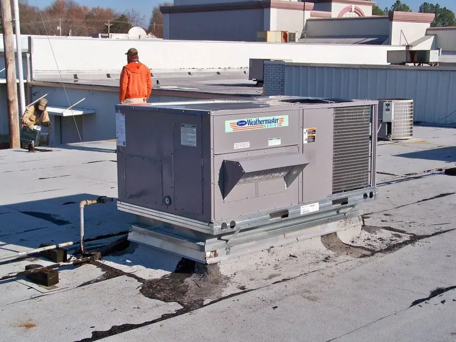 A Carrier Weathermaker rooftop unit with a technician in orange on the roof
